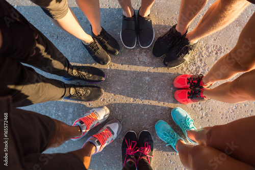 Runners standing in a huddle with their feet together photo