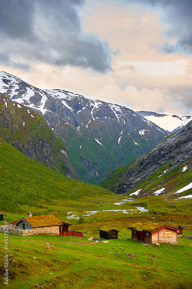 Norwegian mountain houses in a valley under a blue sky.