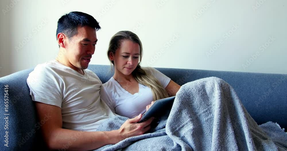 Couple using digital tablet while relaxing on sofa Couple using digital tablet while relaxing on sofa