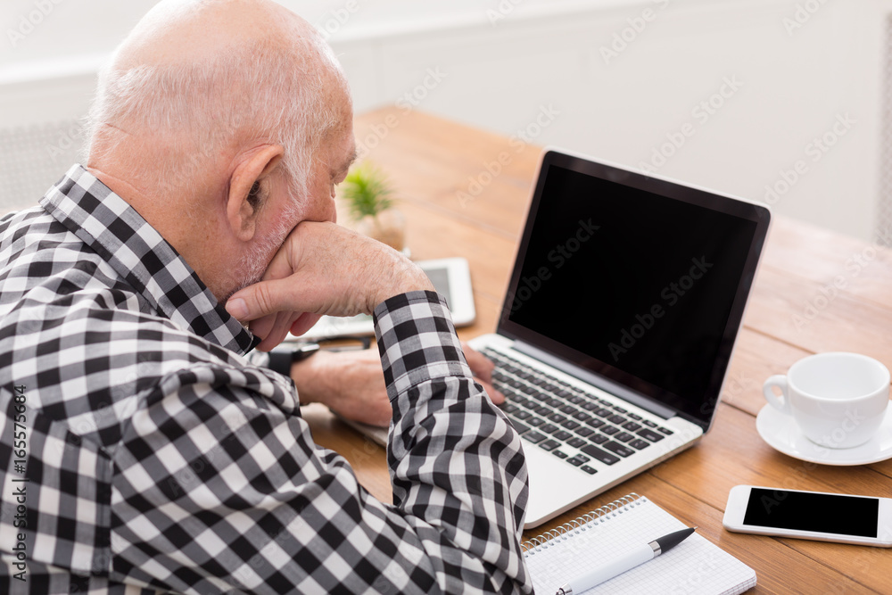 Senior man using laptop with blank screen mockup Senior man using laptop with blank screen mockup