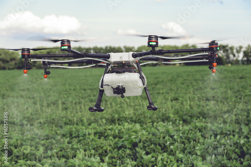 Agriculture drone spraying water or pesticides to grow over green field. Smart farming concept.