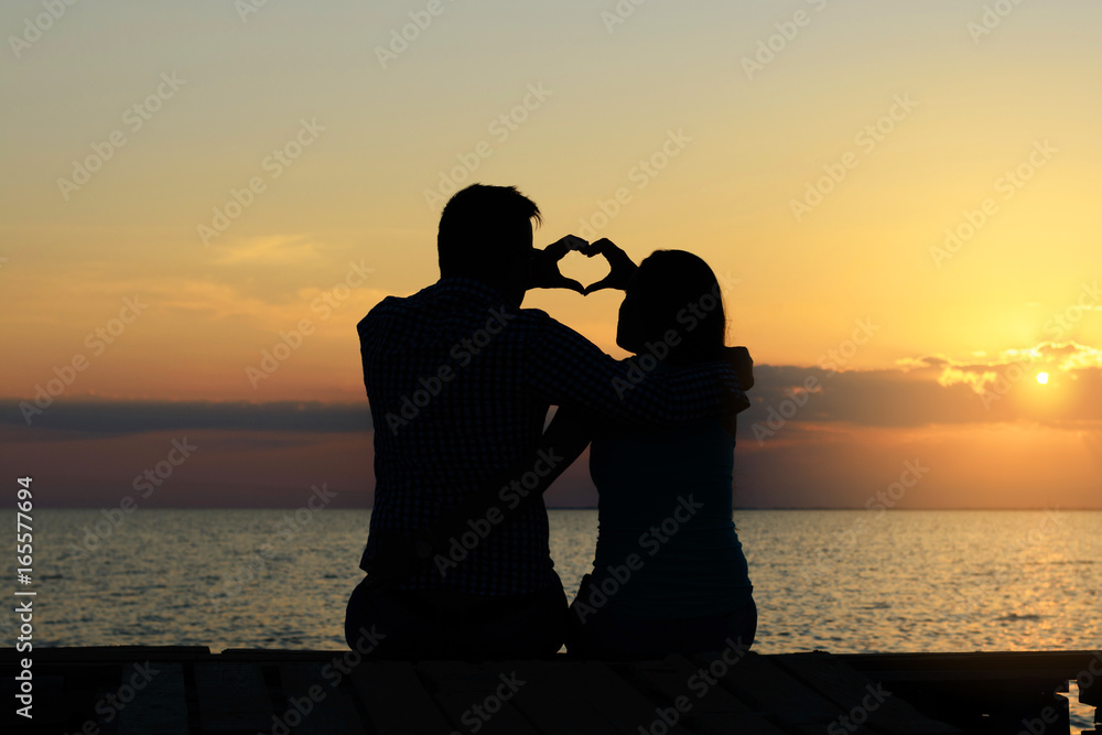 The guy and the girl make from the fingers a heart shape as a symbol of love