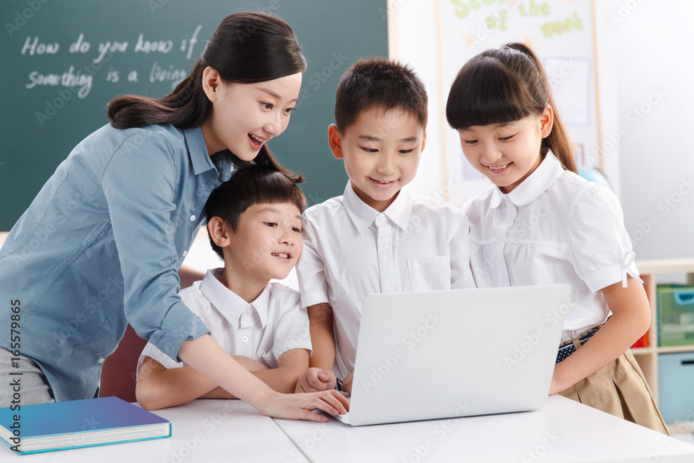 Female teacher helping students studying in classroom Female teacher helping students studying in classroom
