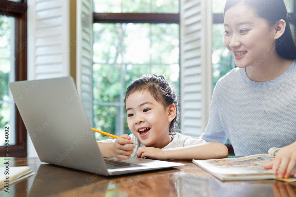 Woman assisting daughter doing homework on laptop Woman assisting daughter doing homework on laptop