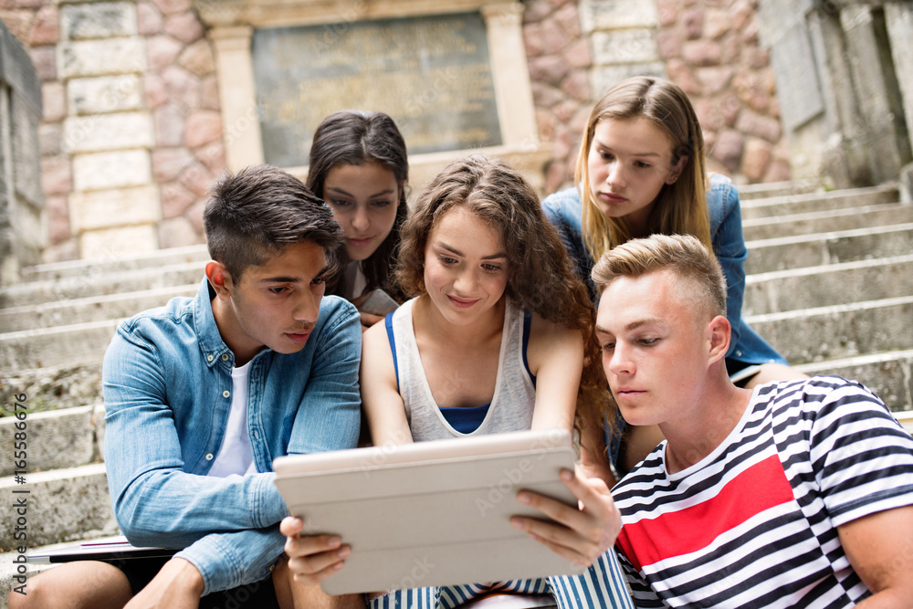 Teenage students with tablet sitting on stone steps. Teenage students with tablet sitting on stone steps.