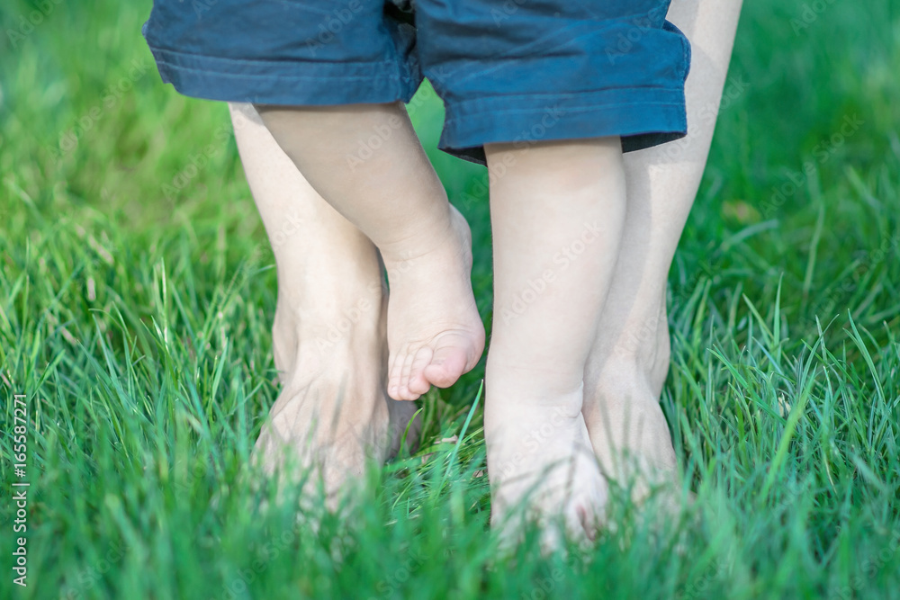 baby and mother feet walking on grass. The fiest steps of child