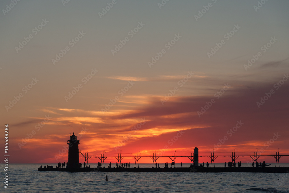 Dramatic view of sunset with lighthouse and pier.
