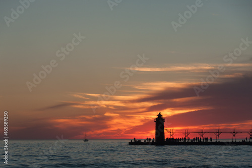 Dramatic view of lighthouse and pier at sunset.