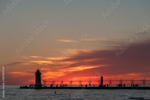 Dramatic view of sunset with lighthouse and pier.