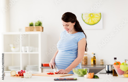 pregnant woman cooking vegetables at home