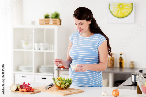 pregnant woman cooking vegetable salad at home © Syda Productions