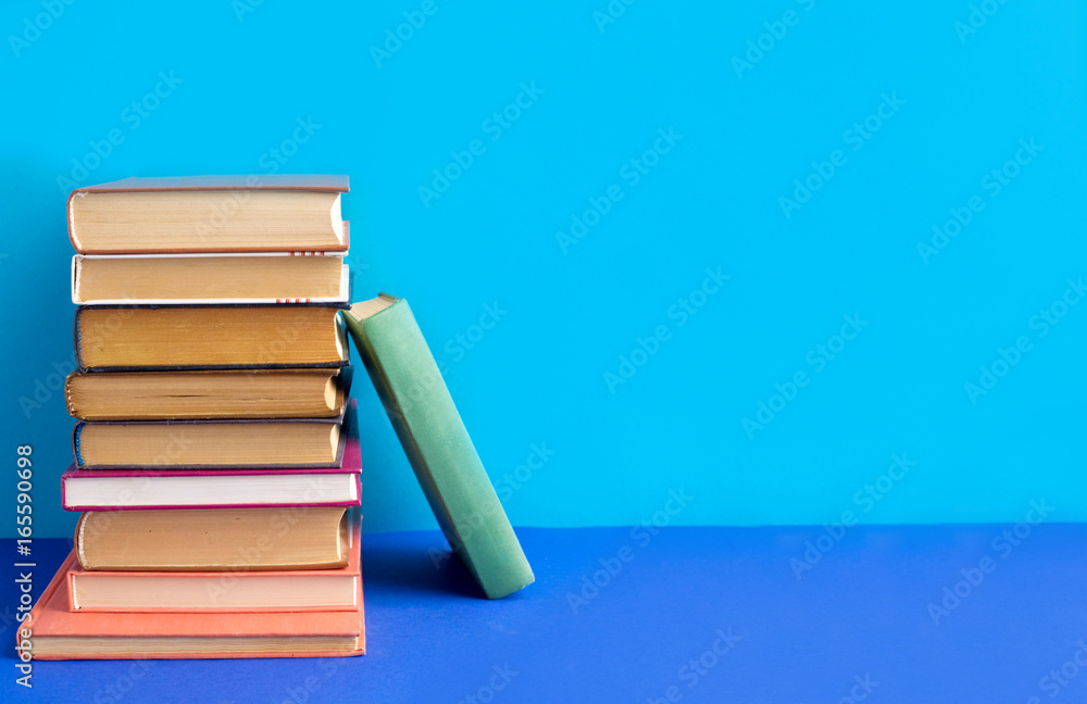 Fototapeta premium Books stacked on a blue background. Textbooks on the table