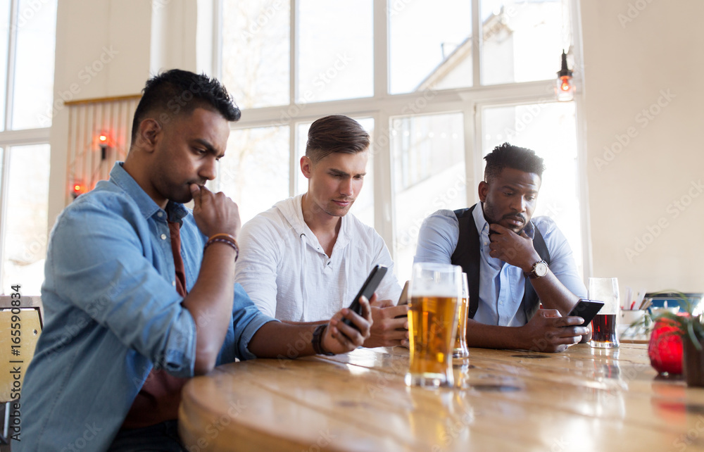 male friends with smartphone drinking beer at bar male friends with smartphone drinking beer at bar