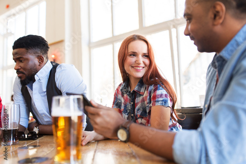 happy friends with tablet pc drinking beer at bar