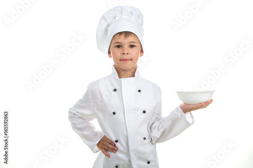 A kid with an empty plate on his hand wearing chef uniform, isolated on white background.