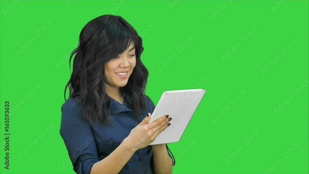Smiling young woman working on tablet computer on a Green Screen, Chroma Key Smiling young woman working on tablet computer on a Green Screen, Chroma Key