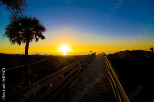 wooden walkway to the beach and ocean sunset