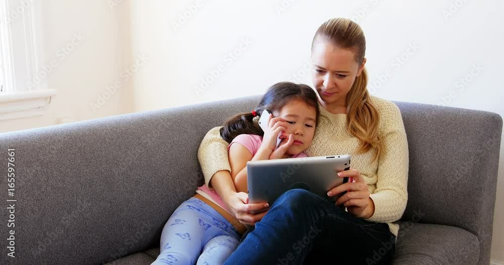 Mother and daughter using digital tablet in living room Mother and daughter using digital tablet in living room