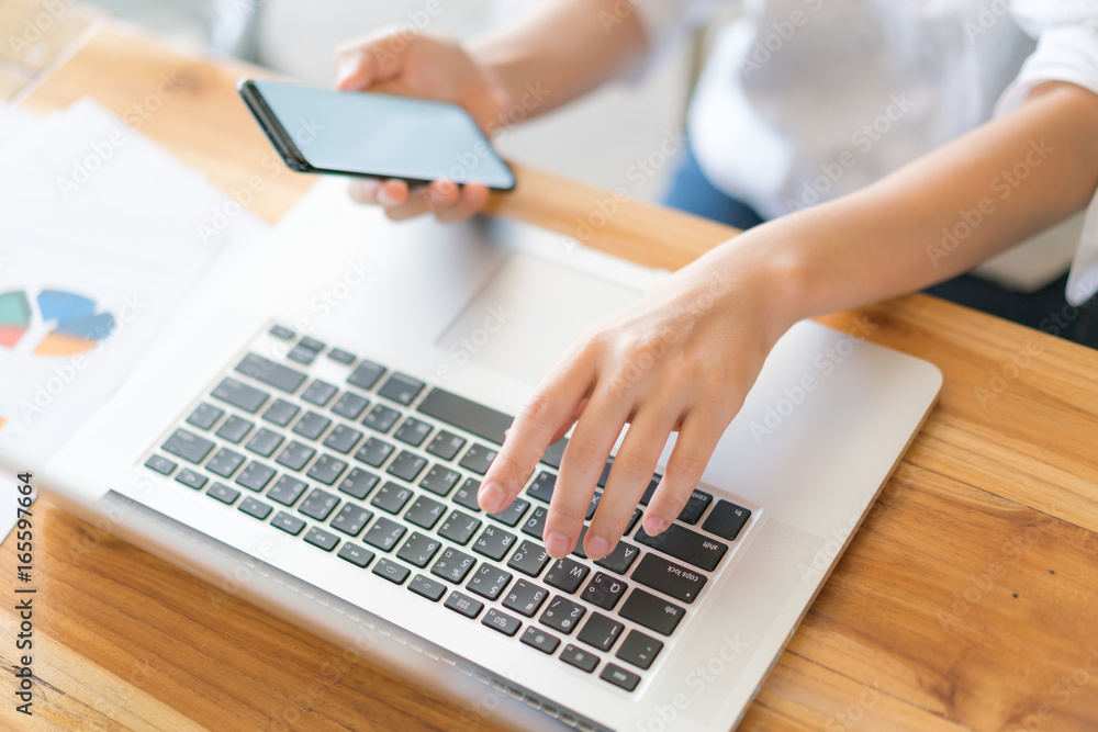 Business woman hand with Financial charts and mobile phone over laptop on the table . Business woman hand with Financial charts and mobile phone over laptop on the table .