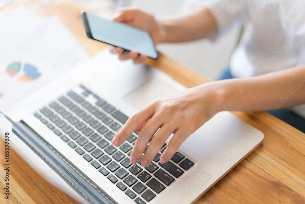 Fototapeta premium Business woman hand with Financial charts and mobile phone over laptop on the table .
