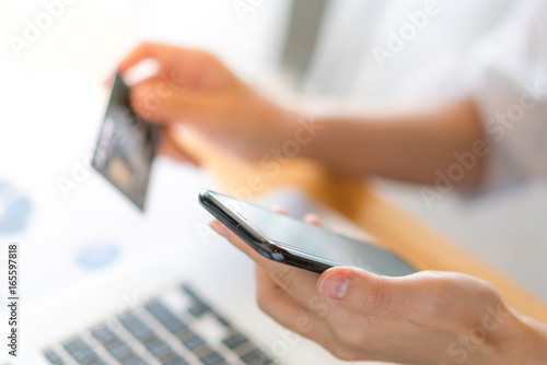 Hands holding a credit card using laptop computer and mobile phone for online shopping