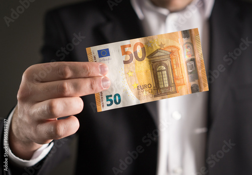 Business man in suit holding the new 50 euro banknote and bill.