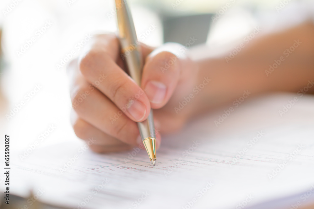 Hand with pen over application form Hand with pen over application form
