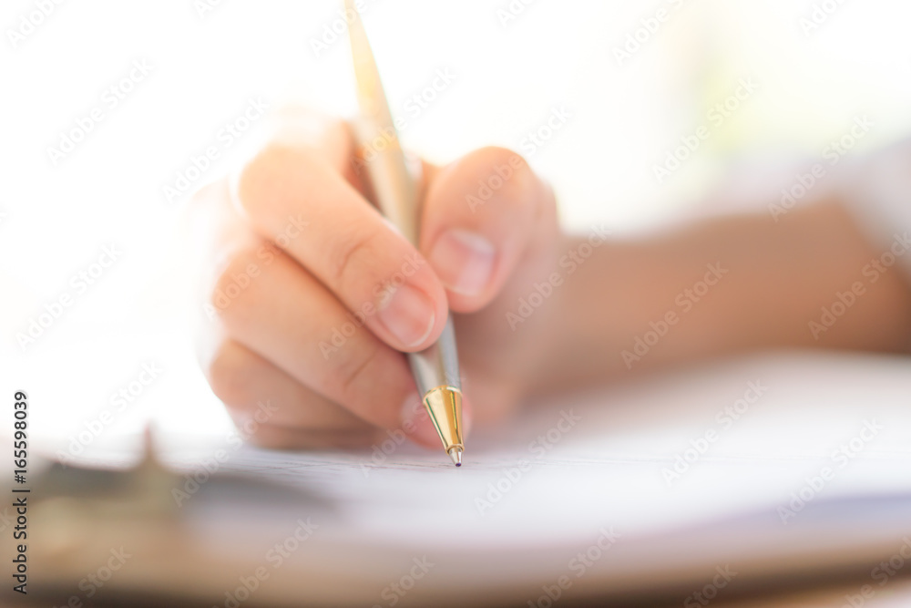 Hand with pen over application form Hand with pen over application form