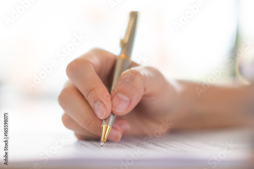 Hand with pen over application form