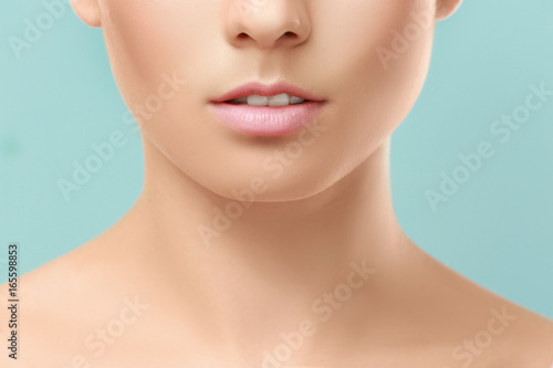 Closeup view of beautiful young woman with natural lips makeup on color background