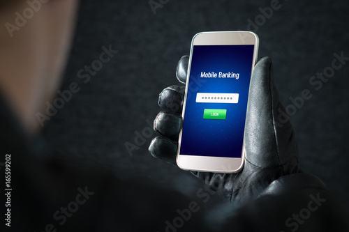 Mobile banking hack and cyber security concept. Hacker and criminal login to persons online bank application and steal money from account with smartphone. Thief with black leather gloves.