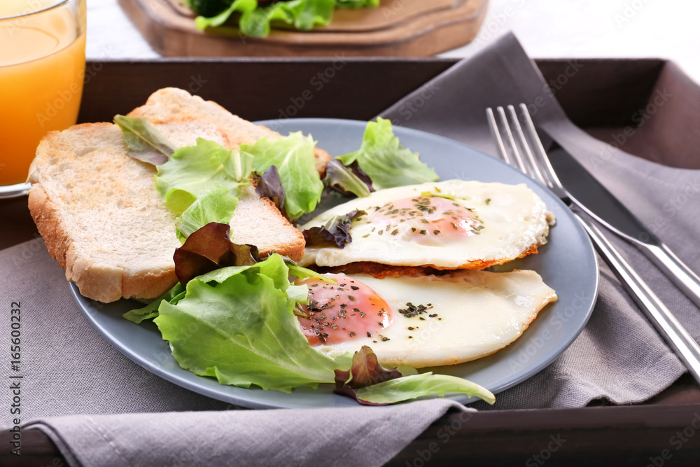 Homemade tasty breakfast with fried eggs on wooden tray