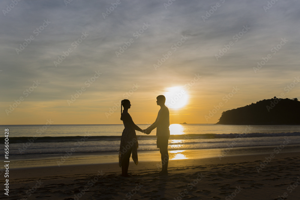 A couple holding hands during an amazing sunset. Loving couple in the pond at sunset hug A couple holding hands during an amazing sunset. Loving couple in the pond at sunset hug