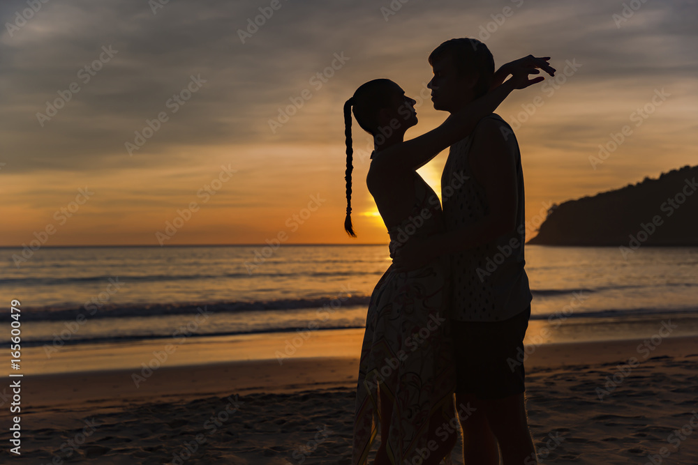 Romantic lovers hugging at twlilight with sunset in background