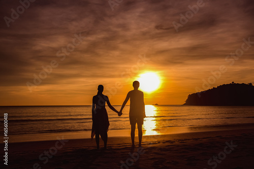 A couple holding hands during an amazing sunset. Loving couple in the pond at sunset hug