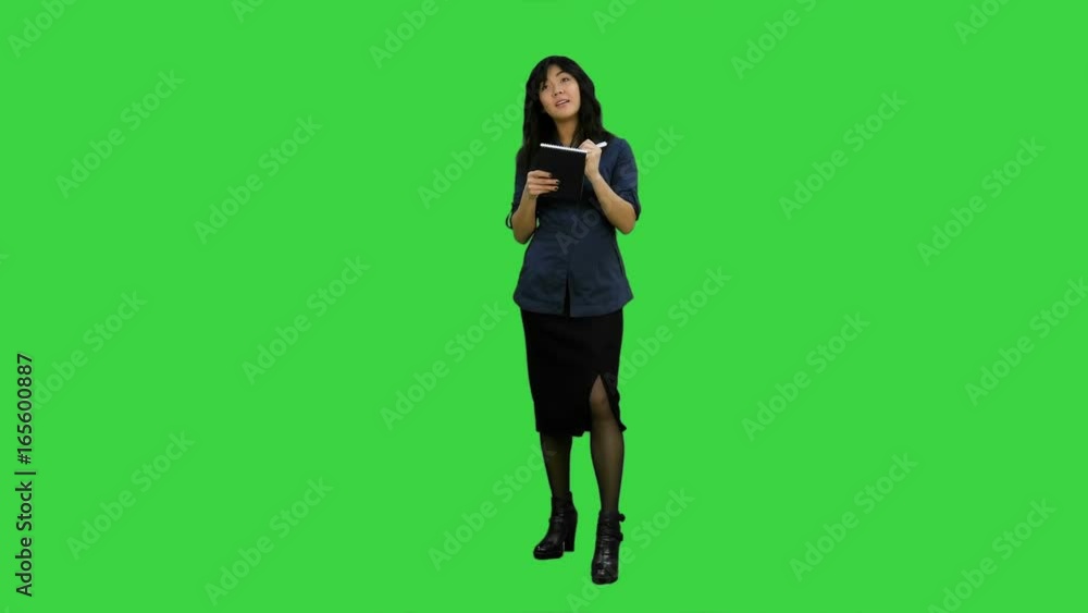 Young asian businesswoman making notes during interview on a Green Screen, Chroma Key Young asian businesswoman making notes during interview on a Green Screen, Chroma Key