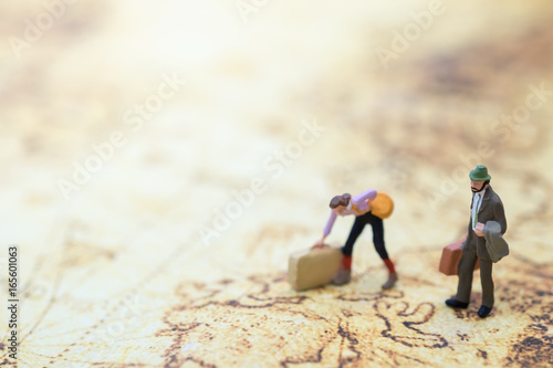 Travel Concept. Man and woamn traveler miniature figures with baggage standing and walking on world map.