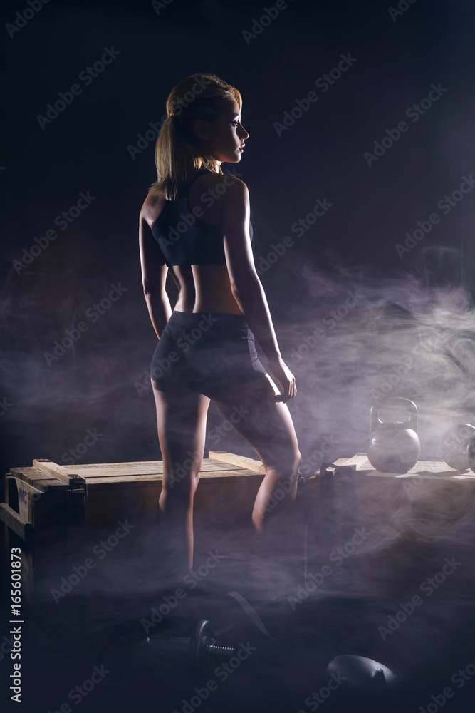Fit and sporty young girl having a training. Dark underground gym. Health, sport, fitness concept. Fit and sporty young girl having a training. Dark underground gym. Health, sport, fitness concept.