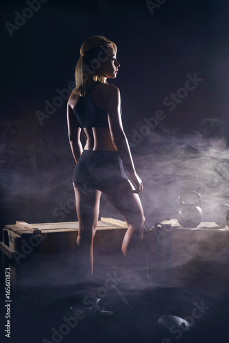 Fit and sporty young girl having a training. Dark underground gym. Health, sport, fitness concept.
