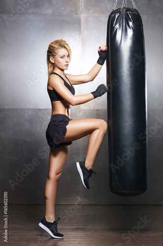 Fit and sporty young girl having a kickboxing training. Underground gym. Health, sport, fitness concept.