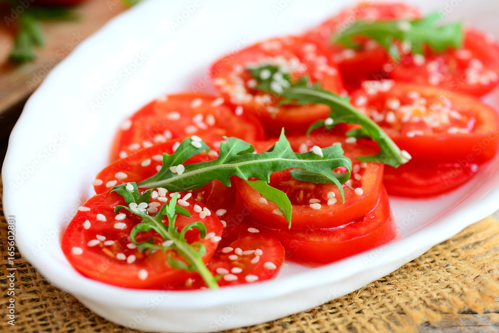 Tomato and arugula salad recipe. Home fresh tomatoes, arugula and sesame seeds salad on a white plate. Quick and healthy vegetarian salad recipe. Closeup Tomato and arugula salad recipe. Home fresh tomatoes, arugula and sesame seeds salad on a white plate. Quick and healthy vegetarian salad recipe. Closeup