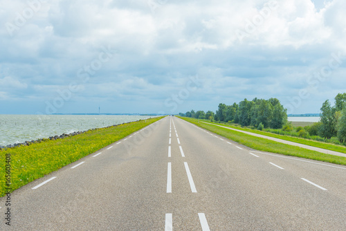 Road over a dike along a lake in summer 