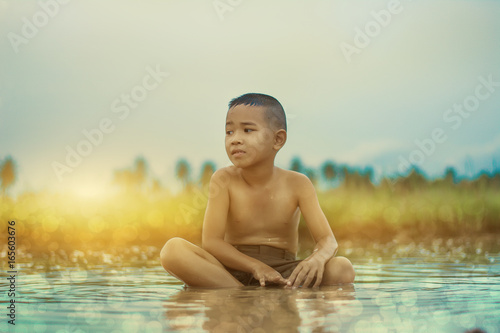 Asian Boy playing in water loosen hot looks happy  Before sunset background  Thailand.