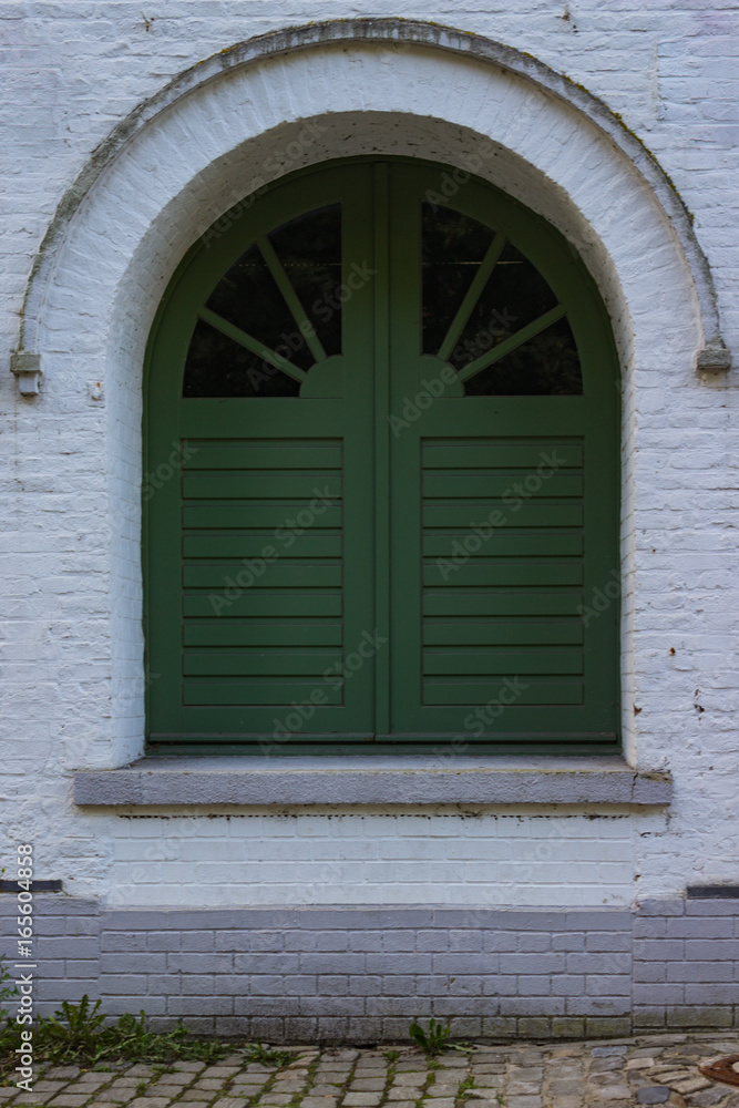 Very old window with green shutters in a white house