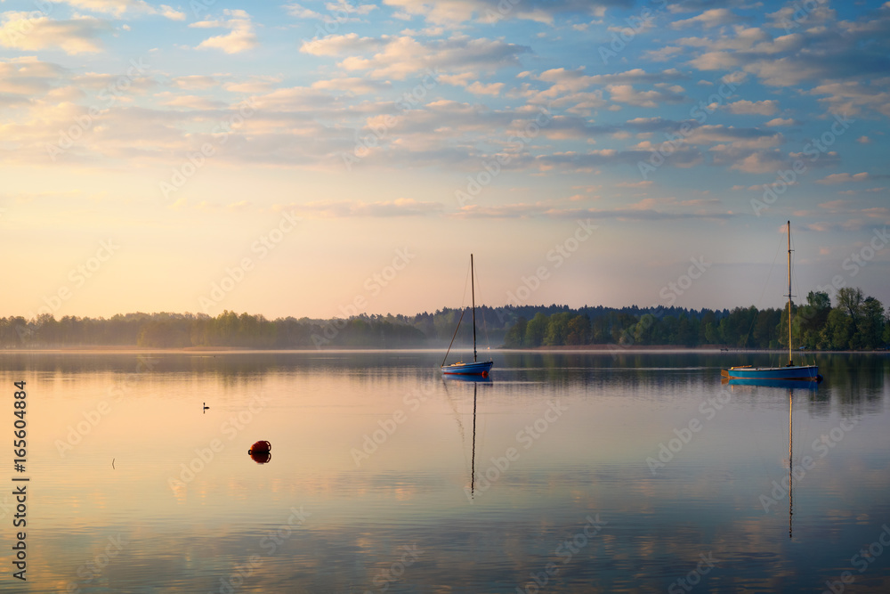 Yachts float on the calm waters of the lake. Early morning. Masuria, Poland . Yachts float on the calm waters of the lake. Early morning. Masuria, Poland .