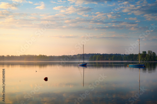 Fototapeta Naklejka Na Ścianę i Meble -  Yachts float on the calm waters of the lake. Early morning. Masuria, Poland .