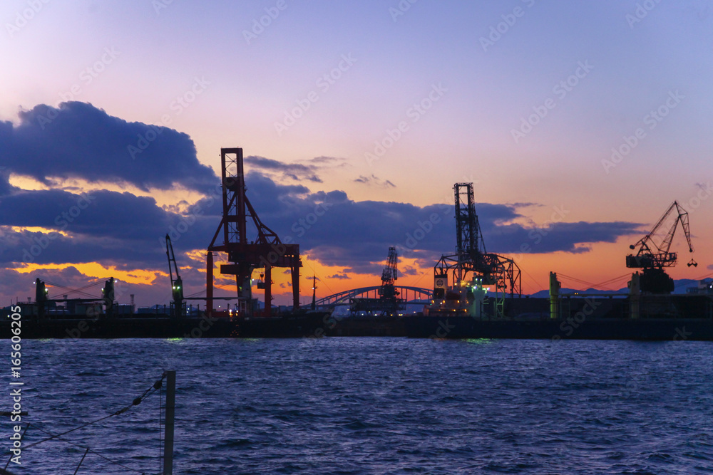 cranes and cargo ships in Tokyo bay at sunset