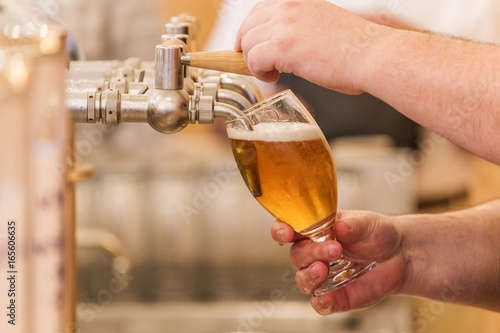 Brewer pours beer into a glass  detail on hand work