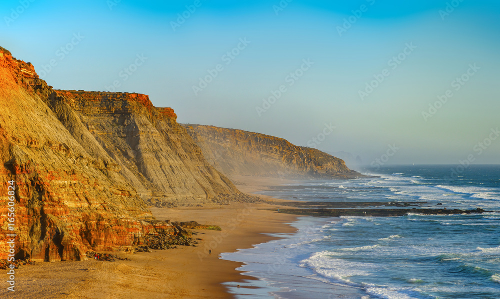 Fototapeta premium Żółte skały i piasek na portugalskim wybrzeżu, żywa woda oceanu