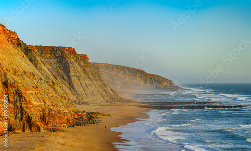Yellow rocks and sand on portuguese coastline, vivid ocean water